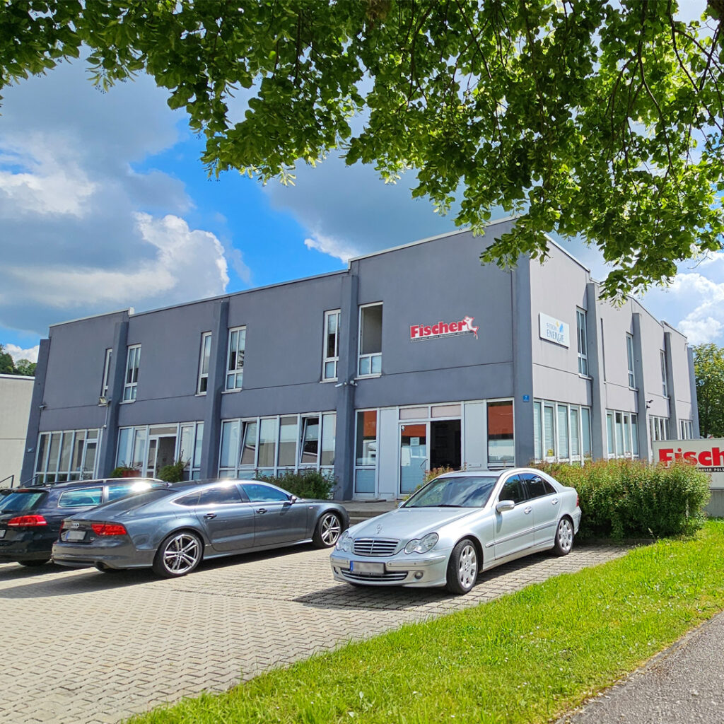 Außenansicht des Verwaltungsgebäudes in Winhöring von Polstermöbel Fischer mit Büroparkplatz und Firmenlogo